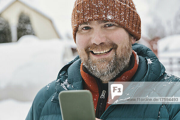 Happy man with mobile phone in winter