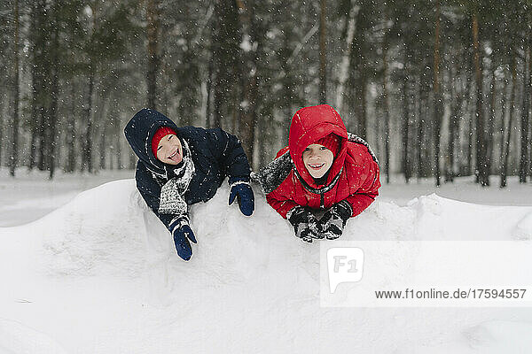 Happy twin brothers playing in snowy forest