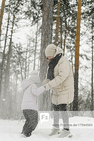 Daughter playing with mother in snowy forest