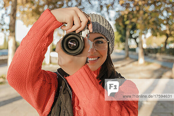 Smiling woman photographing through camera