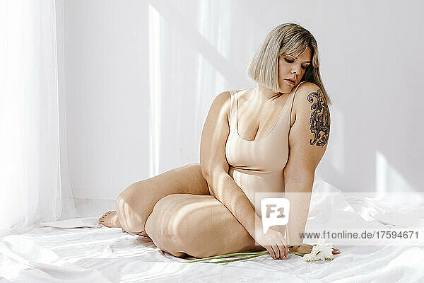 Young curvy blond woman with flowers