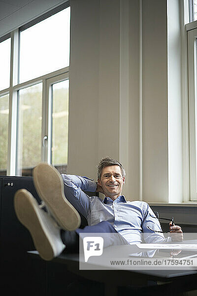 Lächelnder Geschäftsmann  der sich im Büro entspannt