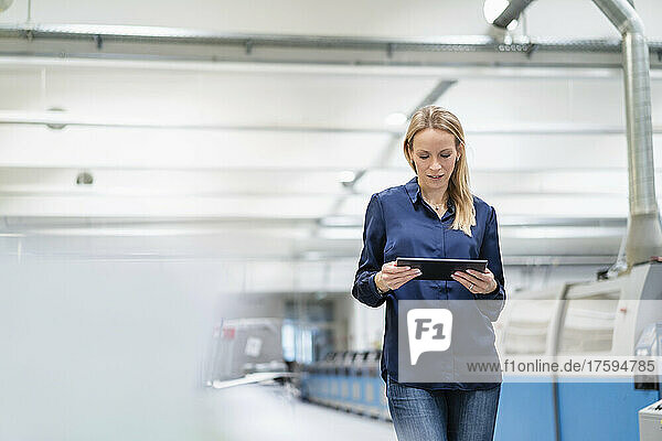 Blond businesswoman using tablet PC in factory