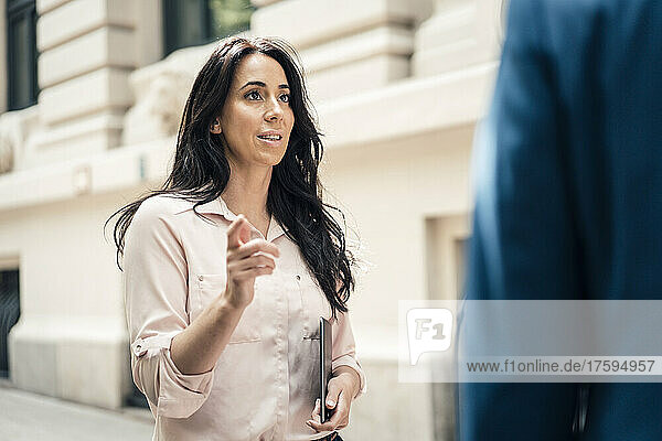 Businesswoman talking with businessman outside building