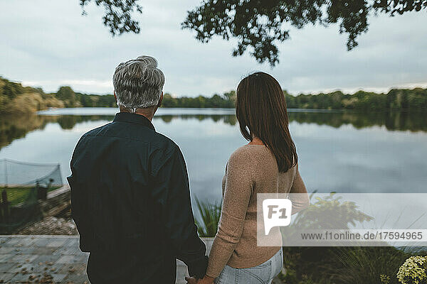 Couple holding hands standing by lake