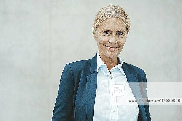 Smiling businesswoman in front of wall