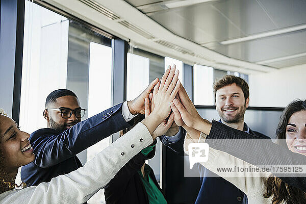 Happy business colleagues with stacked hands in office