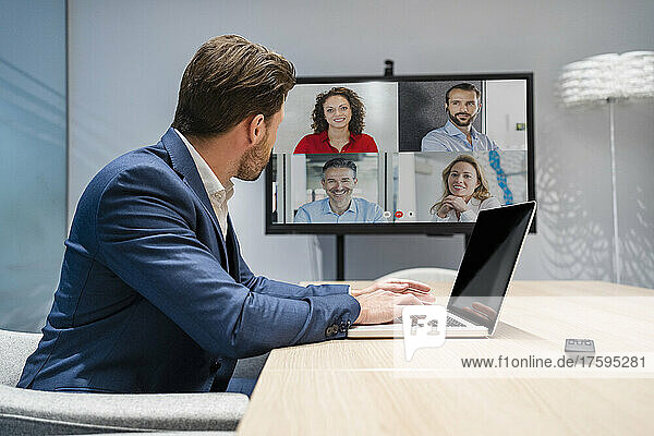 Businessman discussing with colleagues on video call in board room