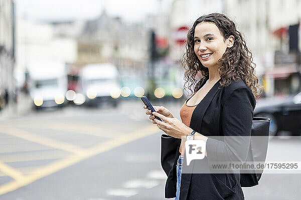 Smiling businesswoman with smart phone in city