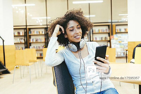 Woman with headphones around her neck using smart phone