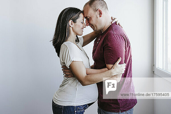 Mann umarmt schwangere Frau zu Hause
