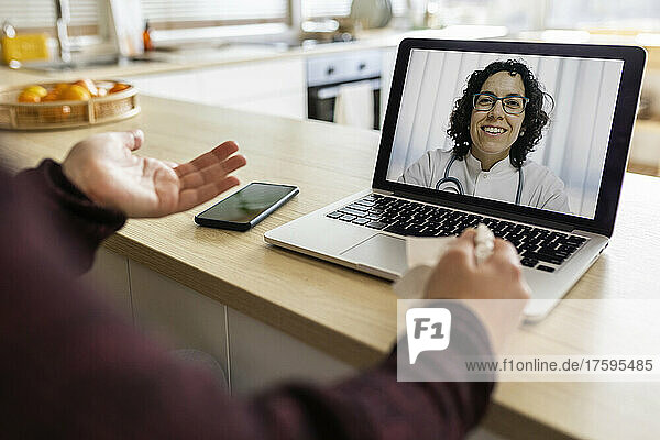 Frau führt zu Hause Videoanruf mit Arzt am Laptop