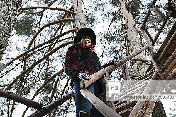 Lächelnde Frau auf Baumhausstufen im Wald
