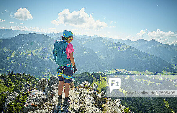 Frau mit Rucksack steht auf dem Gipfel des Berges