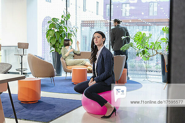Selbstbewusste Geschäftsfrau sitzt im Büro auf einem Trichterball