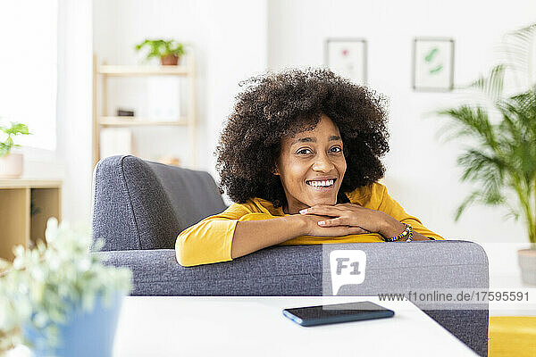 Happy young woman on sofa in living room at home