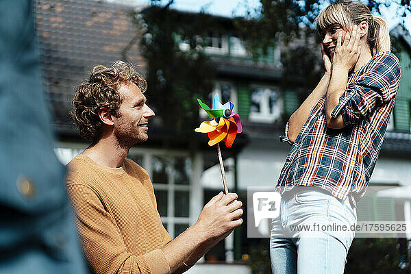 Young man proposing to woman with pinwheel