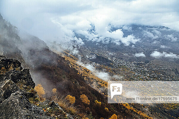 Russia  Dagestan  Gunib  Low clouds over Caucasus Mountains in autumn with village in background