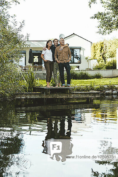 Mann mit Vater und Sohn steht am See im Hinterhof