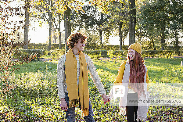 Smiling couple holding hands standing together at park
