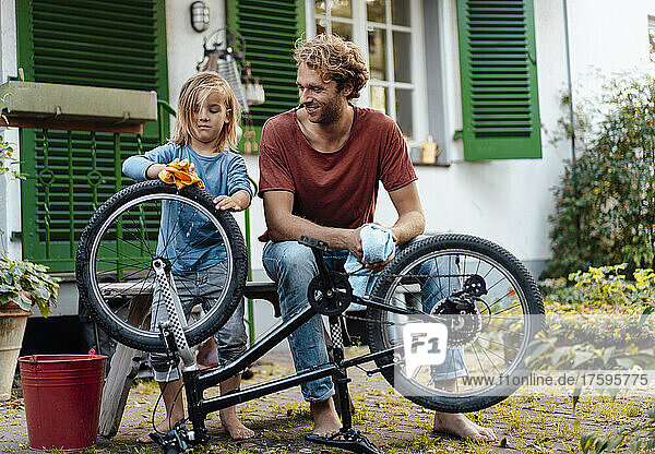 Junge putzt Fahrrad von Vater im Hinterhof