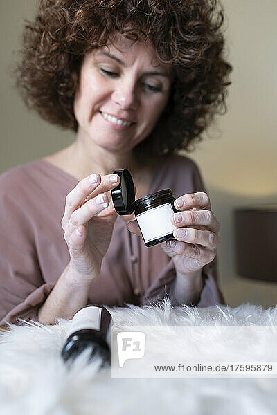 Smiling woman with beauty products at home