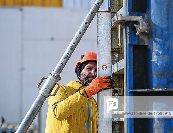 Worker measuring formwork with spirit level at construction site