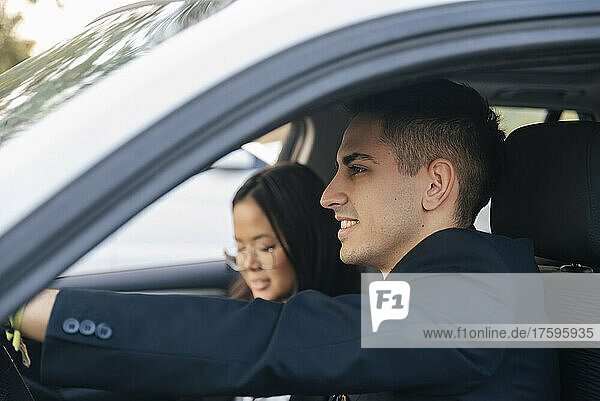 Smiling businessman with colleague sitting in car