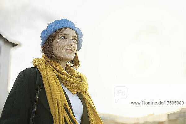 Beautiful woman wearing blue beret and yellow scarf on sunny day
