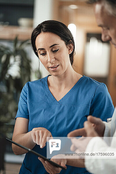 Nurse explaining doctor over tablet PC in hospital
