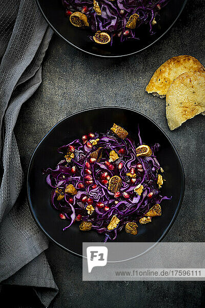 Studio shot of two bowls of vegan salad with red cabbage  pomegranate seeds  dried figs and walnuts