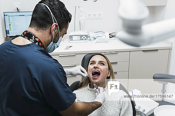 Dentist checking patient's teeth in medical room at clinic