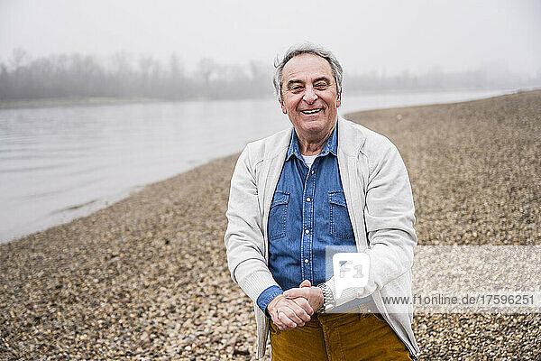 Happy man standing with hands clasped at beach