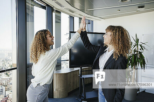 Businesswomen giving high-five to each other at office