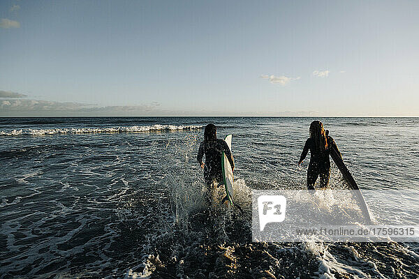Women with surfboards walking in sea  Gran Canaria  Canary Islands