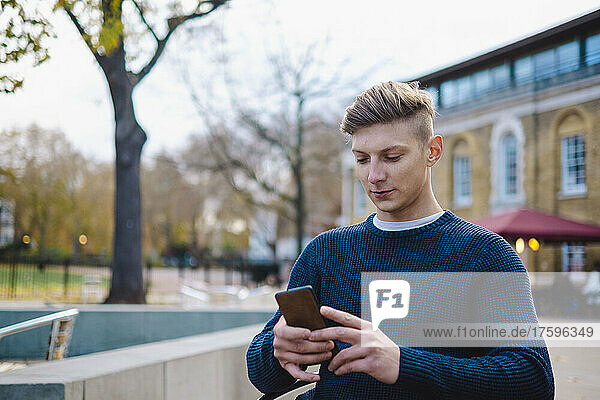 Young man using smart phone on city street