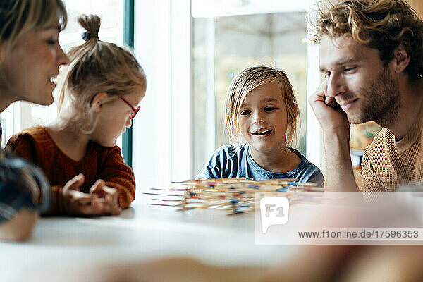 Family playing mikado on table at home