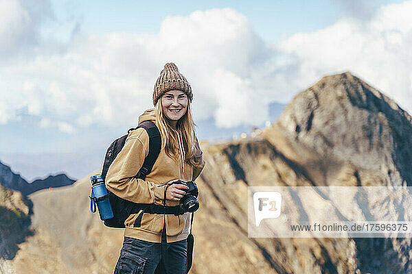 Smiling tourist with backpack and digital camera in front of Caucasus mountains in Sochi  Russia