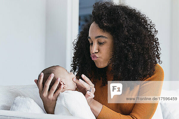 Mother puckering and looking at baby boy in living room