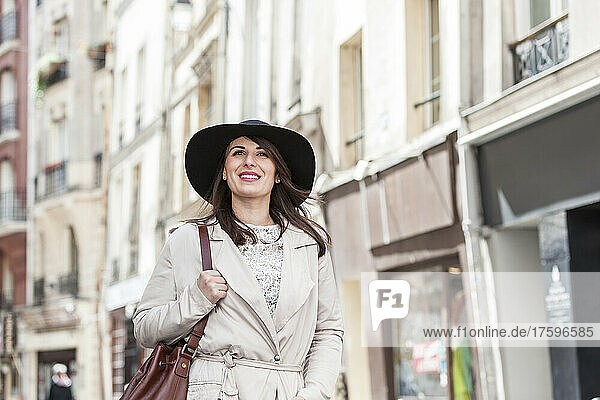 Glückliche Frau mit Hut  die durch die Stadt spaziert