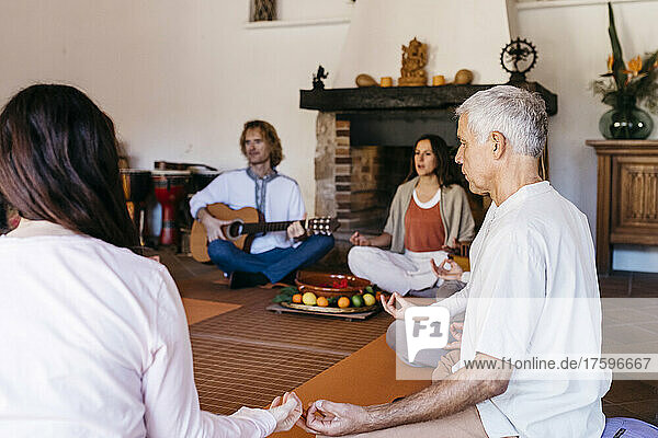 Multiracial friends meditating at music therapy