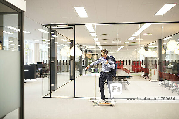 Businessman riding skateboard in modern office