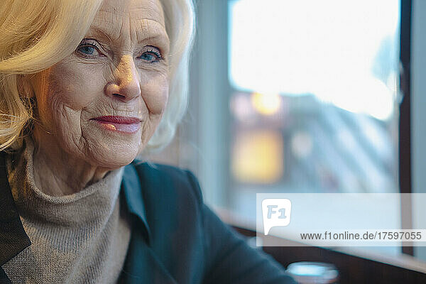 Smiling senior woman sitting by window at cafe