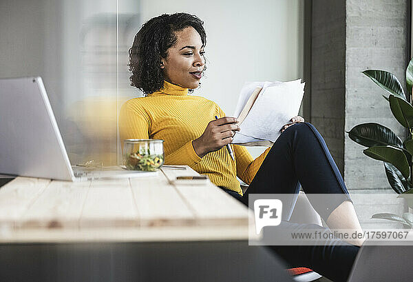 Young businesswoman reading paper document at work place