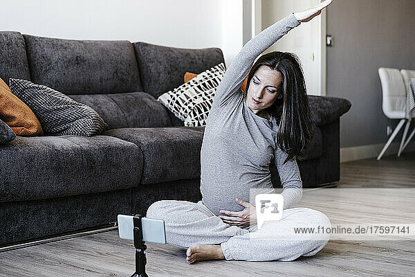 Pregnant woman doing home workout through smart phone