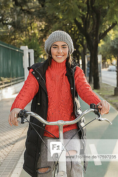 Lächelnde junge Frau  die auf dem Fahrradweg radelt