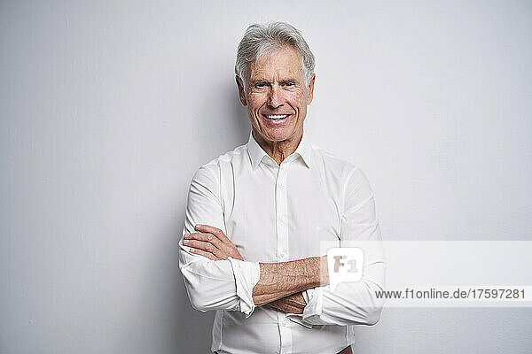 Confident businessman with arms crossed in front of white background