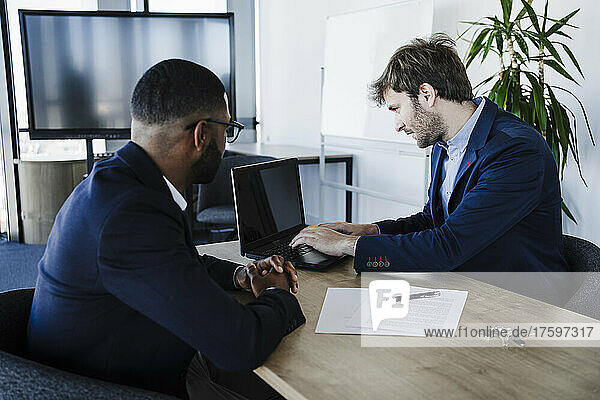 Client with businessman working on laptop in office