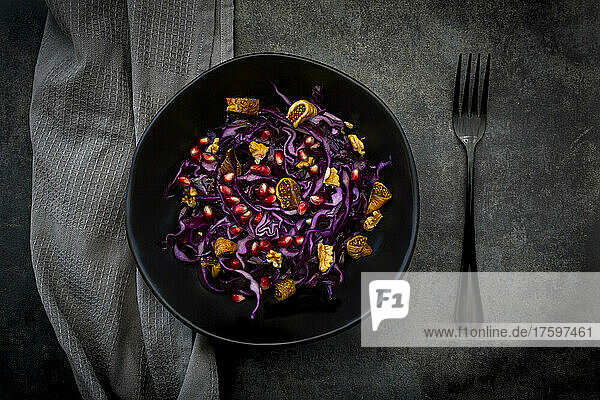 Studio shot of bowl of vegan salad with red cabbage  pomegranate seeds  dried figs and walnuts