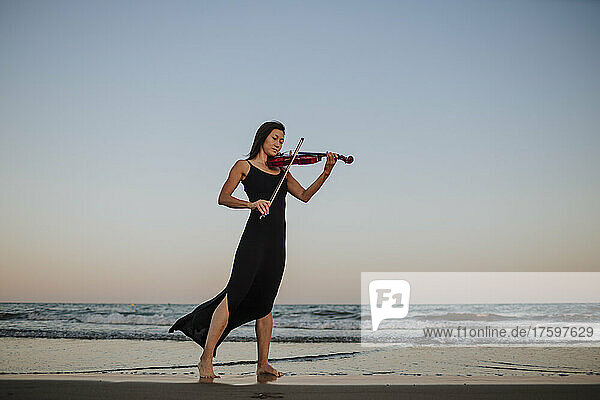 Woman playing violin by sea at beach